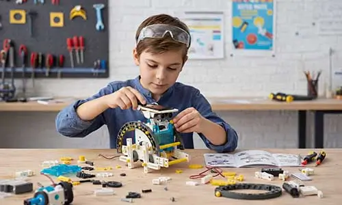 Menino concentrado montando um Kit de Robótica Solar, um dos jogos educativos que ensinam energia renovável e engenharia mecânica de forma prática e divertida