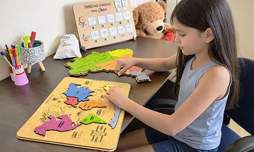 Criança usando jogos educativos de encaixe em madeira, brinquedo pedagógico ideal para aprender geografia, desenvolver foco e coordenação motora.
