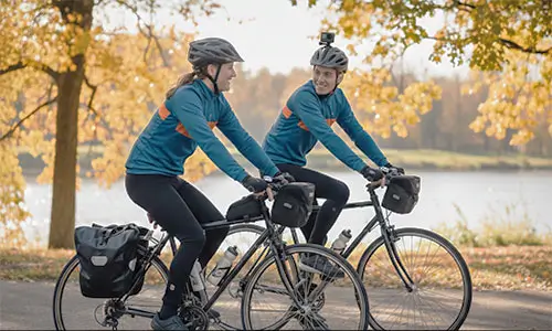 Casal, em momento de lazer, pedalando com suas bikes equipadas e usando EPI´s