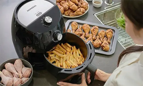 A air fryer gasta muita energia? Air Fryer Mondial mostrando coxas de frango douradas e suculentas após o preparo.