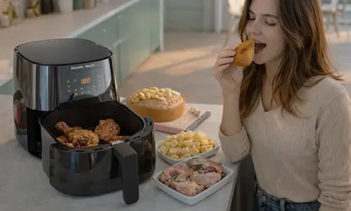 A air fryer gasta muita energia? Air Fryer Walita. O cesto aberto, revela batatas fritas douradas e crocantes, levemente salpicadas com orégano.